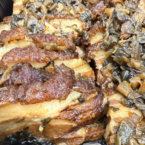 Close-up of braised pork belly with a dark background