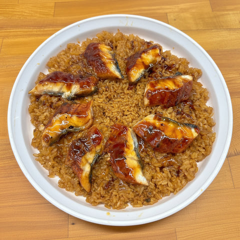 Platter of rice with fish pieces on a wooden surface