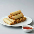 Spring rolls stacked on a green leafy plate