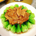 Plated dish of braised chicken with green vegetables on a white plate.